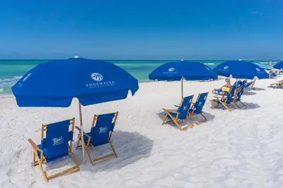 a row of blue chairs and umbrellas on a beach at Edgewater Beach & Golf Resort by Panhandle Getaways in Panama City Beach