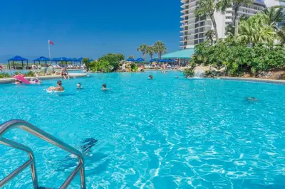 a group of people swimming in a swimming pool at Edgewater Beach & Golf Resort by Panhandle Getaways in Panama City Beach
