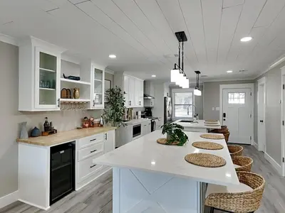 a kitchen with white cabinets and a large island with stools at Easy on Eastern Lake in Santa Rosa Beach