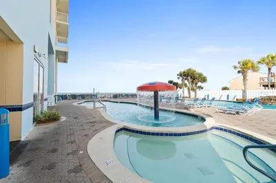 a swimming pool with an umbrella and chairs and a beach at Majestic Beach Resort Tower I by Panhandle Getaways in Panama City Beach