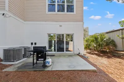 a patio in front of a house with a grill at Sailors Cove: 5-Bedroom, 45 Baths, Sleeps 12! Steps Away from the Beach! in Panama City Beach