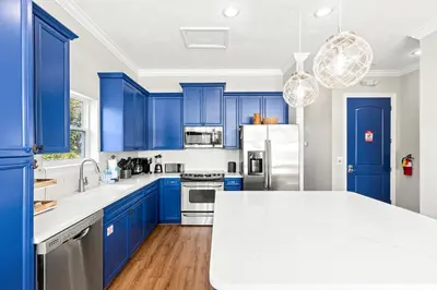 a blue kitchen with white counters and blue cabinets at Sailors Cove: 5-Bedroom, 45 Baths, Sleeps 12! Steps Away from the Beach! in Panama City Beach