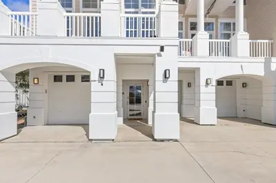 a white house with four garage doors at Sailors Cove: 5-Bedroom, 45 Baths, Sleeps 12! Steps Away from the Beach! in Panama City Beach