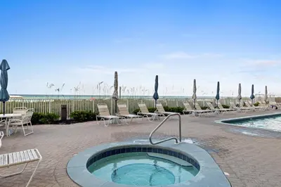 a hot tub in a patio with chairs and a pool at Ocean Ritz by Panhandle Getaways in Panama City Beach