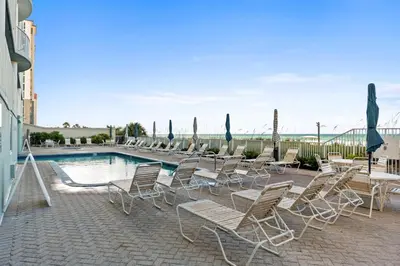 a group of chairs and a swimming pool with umbrellas at Ocean Ritz by Panhandle Getaways in Panama City Beach