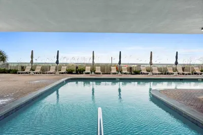 a swimming pool with chaise lounge chairs and a beach at Ocean Ritz by Panhandle Getaways in Panama City Beach