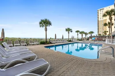 a swimming pool with lounge chairs and palm trees at Ocean Villa by Panhandle Getaways in Panama City Beach