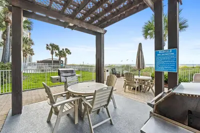 a patio with a table and chairs and a grill at Ocean Villa by Panhandle Getaways in Panama City Beach