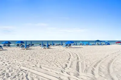 a beach with chairs and blue umbrellas and the ocean at Ocean Villa by Panhandle Getaways in Panama City Beach