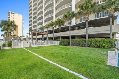 a grassy yard in front of a building with palm trees at Ocean Villa by Panhandle Getaways in Panama City Beach