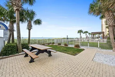 a picnic table in a park with palm trees at Ocean Villa by Panhandle Getaways in Panama City Beach
