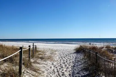 a sandy beach with a fence and the ocean at Portside Resort by Panhandle Getaways in Panama City Beach