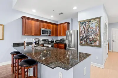 a kitchen with a granite counter top and wooden cabinets at Reflections by Panhandle Getaways in Panama City Beach