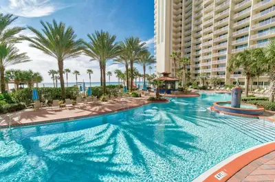 a pool at the resort with palm trees and a building at Shores of Panama by Panhandle Getaways in Panama City Beach