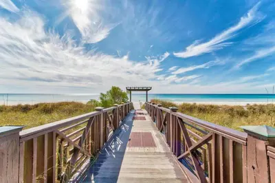 a wooden walkway to the beach with the ocean in the background at Shores of Panama by Panhandle Getaways in Panama City Beach