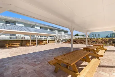 a picnic table and benches under a pavilion at Southwind by Panhandle Getaways in Panama City Beach