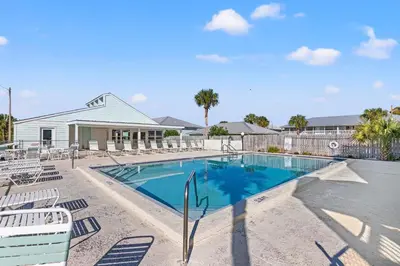a swimming pool with lounge chairs and a house at Southwind by Panhandle Getaways in Panama City Beach