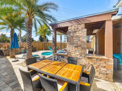 a patio with a wooden table and chairs and palm trees at Orange Crush in Panama City Beach