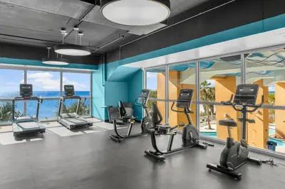 a gym with cardio equipment in a building with windows at Splash Beach Resort by Panhandle Getaways in Panama City Beach