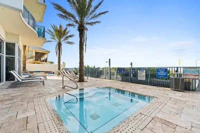 a swimming pool on a patio with a palm tree at Sterling Breeze by Panhandle Getaways in Panama City Beach