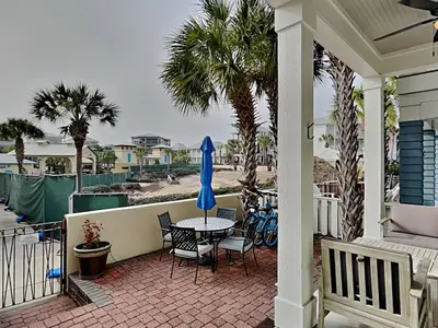 a patio with a table and chairs and palm trees at Sunny Side Up in Inlet Beach