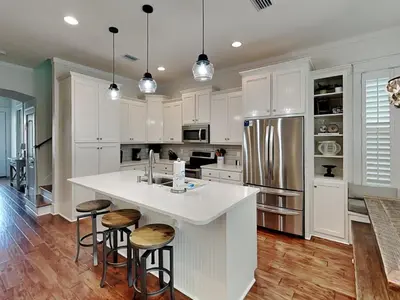 a kitchen with white cabinets and a kitchen island with stools at Sunny Side Up in Inlet Beach