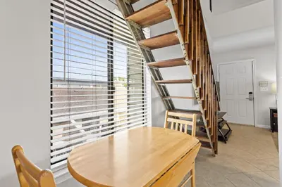 a dining room with a wooden table and a spiral staircase at Sunswept by Panhandle Getaways in Panama City Beach