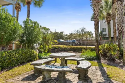a picnic table and benches in a park with palm trees at Sunswept by Panhandle Getaways in Panama City Beach