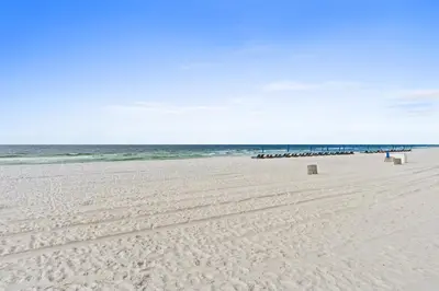 a sandy beach with benches and the ocean at Sunswept by Panhandle Getaways in Panama City Beach