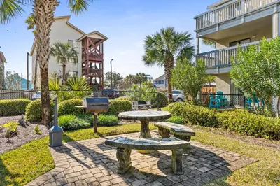 a park with benches and a grill in front of a building at Sunswept by Panhandle Getaways in Panama City Beach