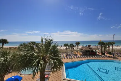 a swimming pool with palm trees and the beach at The Summit by Panhandle Getaways in Panama City Beach