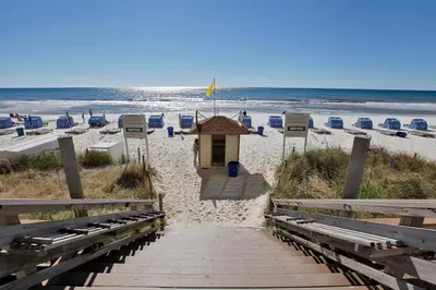 a small building on a beach with chairs and the ocean at Tidewater Beach Resort by Panhandle Getaways in Panama City Beach