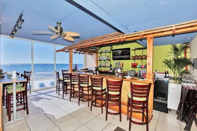 a restaurant with a bar with a view of the ocean at Tidewater Beach Resort by Panhandle Getaways in Panama City Beach