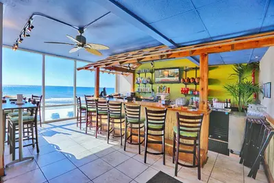 a restaurant with a bar with a view of the ocean at Tidewater Beach Resort by Panhandle Getaways in Panama City Beach