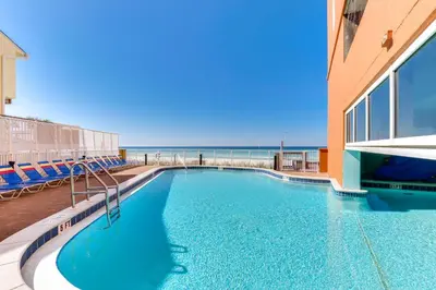 a swimming pool with the ocean in the background at Tropic Winds Resort by Panhandle Getaways in Panama City Beach