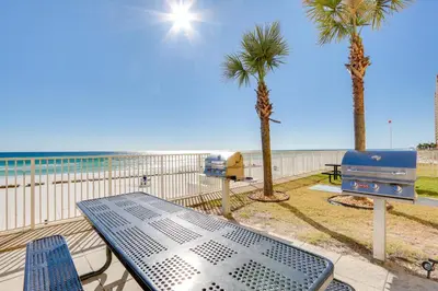 a picnic table and palm trees next to the beach at Tropic Winds Resort by Panhandle Getaways in Panama City Beach
