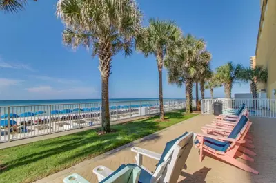 a row of beach chairs and palm trees at the beach at Tropic Winds Resort by Panhandle Getaways in Panama City Beach