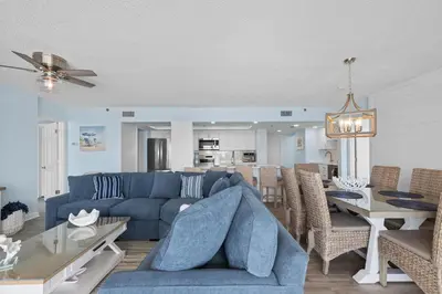 a living room with a blue couch and a dining room at Come Enjoy KC & The Sunshine State: 3-Bed, 3-Bath With Stunning Ocean Views in Panama City Beach