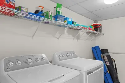 a laundry room with a washing machine and a shelf at Come Enjoy KC & The Sunshine State: 3-Bed, 3-Bath With Stunning Ocean Views in Panama City Beach