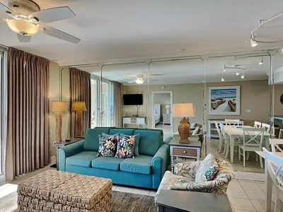 a living room with a blue couch and a dining room at Emerald Beach #2531 in Panama City Beach