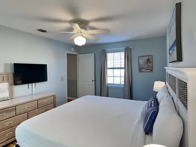 a bedroom with a white bed and a flat screen tv at Horizon South #76G in Panama City Beach
