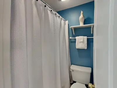 a bathroom with a white shower curtain and a toilet at Horizon South #76G in Panama City Beach