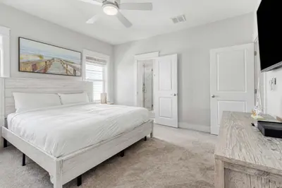 a white bedroom with a bed and a table at Modern Coastal Escape with Fire Pit & Pool Access in Inlet Beach