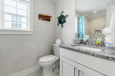 a bathroom with a toilet and a sink and a window at Modern Coastal Escape with Fire Pit & Pool Access in Inlet Beach