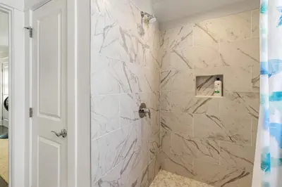 a bathroom with a shower with marble tiles at Modern Coastal Escape with Fire Pit & Pool Access in Inlet Beach