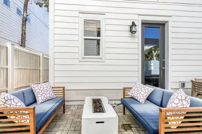 a patio with two blue couches and a coffee table at Modern Coastal Escape with Fire Pit & Pool Access in Inlet Beach