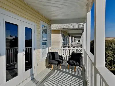 a balcony with two chairs on a house at Sunset On Seabreeze in Inlet Beach