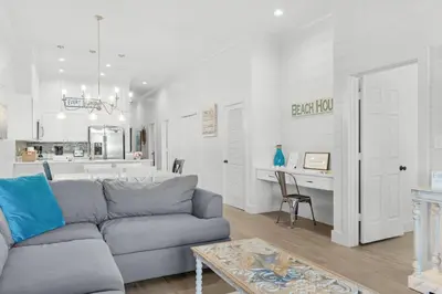 a living room with a gray couch and a kitchen at The Village Happy Life Condo - Private Beach Access Pool & Hot Tub in Rosemary Beach