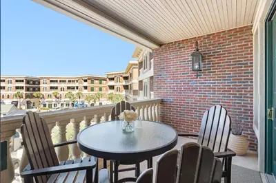 a patio with a table and chairs on a balcony at The Village Happy Life Condo - Private Beach Access Pool & Hot Tub in Rosemary Beach