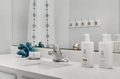 a bathroom counter with two bottles of soap and a sink at The Village Happy Life Condo - Private Beach Access Pool & Hot Tub in Rosemary Beach